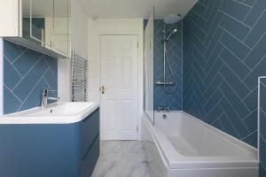 a bathroom with a tub and a sink and blue tiles at Ocean Parc in Carbis Bay +33 photos