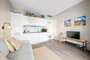 a living room with a couch and a television at La Plage - Studio - Face à la Mer - Clim Terrasse in Menton