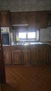 a kitchen with wooden cabinets and a sink and a window at Aveiro, Veneza Portuguesa in Oliveirinha