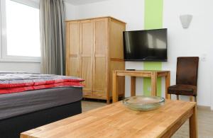 Apartments Blütenweg في لايشلينغن: غرفة نوم بسرير وطاولة وتلفزيون