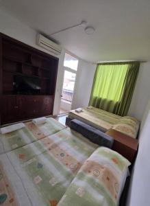 a bedroom with two beds and a window with green curtains at EDIFICIO BENHUr in Cúcuta