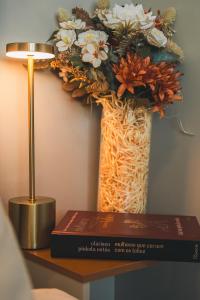 a vase filled with flowers on a table with a book at VIVA - Centro - Garagem - Apt 1 Dormitório in Santa Maria