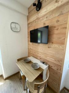 a dining room with a table and a tv on a wall at Gallice Bey in Briançon