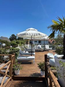 a deck with white lounge chairs and an umbrella at Marie Siska Boutique hotel in Knokke-Heist