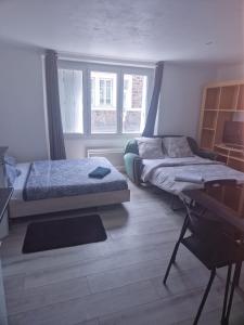 a bedroom with two beds and a desk and windows at Studio la Romagne in La Romagne