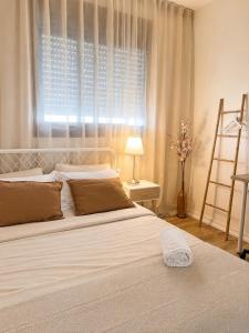 a bedroom with a large white bed with a window at אמור in Beer Sheva