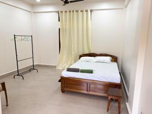 a bedroom with a bed with white sheets and a window at LN Homes in Itānagar