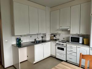 a kitchen with white cabinets and a sink and a microwave at Kätevä Koti Keskustassa in Ähtäri