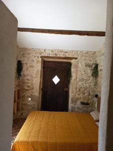 a bedroom with a wooden door in a stone wall at Chambre du petit figuier in Aramon