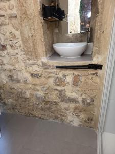 a bathroom with a sink in a stone wall at Chambre du petit figuier in Aramon