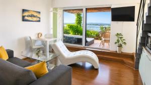 a living room with a couch and a tv and a balcony at Apartmán Pálava 1 s terasou a výhledem na jezero in Pavlov