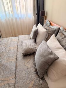 a bed with pillows on top of it at На 2 мин от плажа!Victoria- две спални делукс до Морската градина и центъра in Burgas