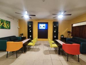 a waiting room with tables and chairs and a tv at Urbania Office Hotel in Tuxtla Gutiérrez