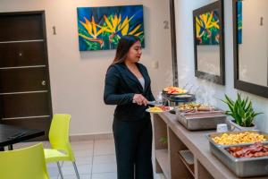 a woman standing in front of a buffet of food at Urbania Office Hotel in Tuxtla Gutiérrez