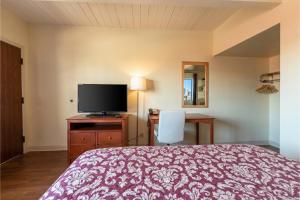 a bedroom with a bed and a flat screen tv at Travelers Inn by OYO Longview Kelso in Longview