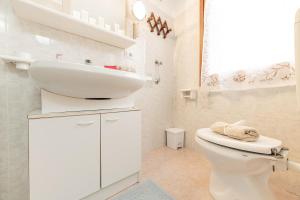 a white bathroom with a sink and a toilet at Puria Rustic Lake View Apartment in Valsolda +27 photos