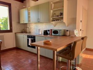 a kitchen with white cabinets and a wooden table at Dolce Collina, Sunset Terrace & Vineyard Views in Dozza