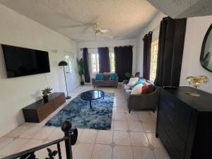 a living room with a couch and a tv at Ackee Haven Comfortable Spacious Home in Poor Mans Corner