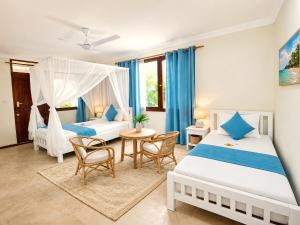 a bedroom with two beds and a table and chairs at HA Beach Breeze in Jambiani