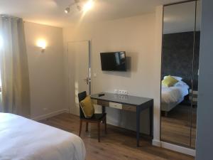 a bedroom with a desk with a bed and a tv at Hotel de Normandie in Évreux