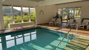 a large swimming pool with chairs and tables and windows at WELLNESS Hotel UHLENBERG in Bad Münstereifel