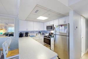 a kitchen with white cabinets and a stainless steel refrigerator at Crystal Sands 403 in Ocean City