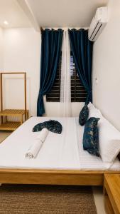 a large white bed with blue pillows and a window at Serene Abodes in Zanzibar City