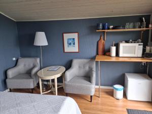 a bedroom with two chairs and a table with a microwave at Vandrarhemmet Tallbacka/Ängelsberg Hostel in Ängelsberg