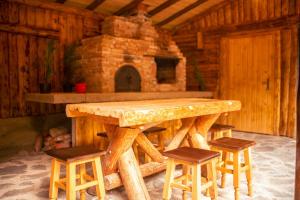 a wooden table and stools in a room with a fireplace at Cabana La Urși in Ceraşul