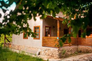 a house with a porch and a stone wall at Cabana La Urși in Ceraşul