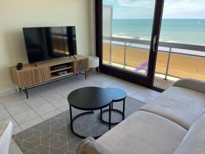 a living room with a couch and a tv and a table at Studio Zeester in Westende-Bad +5 photos