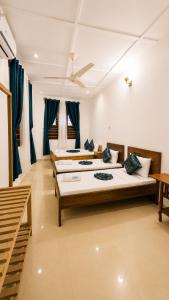three beds in a room with blue curtains at Serene Abodes in Zanzibar City