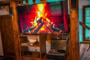 a tv sitting on a stand with a fire on it at Cabana La Urși in Ceraşul