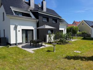 a house with a table and an umbrella in the yard at H24ZINGST - Das Ferienhaus in Zingst