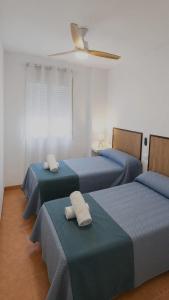 a room with three beds with towels on them at El Akito apartamento in Huéscar