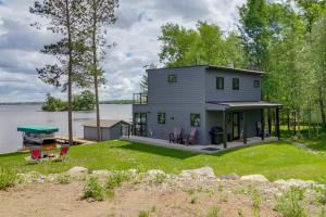 a house on the shore of a body of water at Lakefront Northwoods Cabin w/ Shared Dock & Views! in Tower