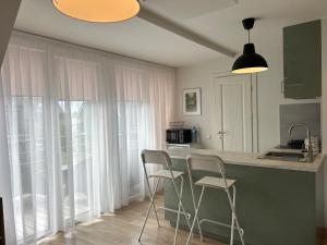 a kitchen with two chairs and a counter with windows at Rainbow Palanga in Palanga