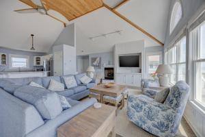 a living room with a blue couch and chairs at 7048 - Tide Song in Rodanthe +33 photos