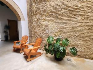 three chairs and a plant next to a brick wall at CAMASanlúcar in Sanlúcar de Barrameda