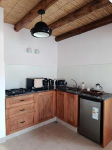a kitchen with wooden cabinets and a black refrigerator at Cabana Mirador Sumajpacha in Tilcara +17 photos