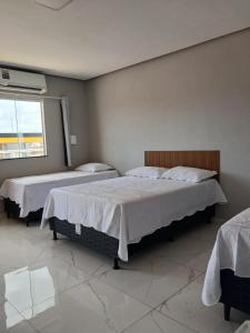 a bedroom with two beds and a window at Pousada Ômega in Caxias das Aldeias Altas