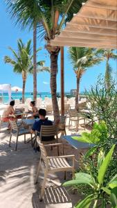 a group of people sitting at tables on the beach at Hotel Garden Flora Punta Cana Beach in Punta Cana