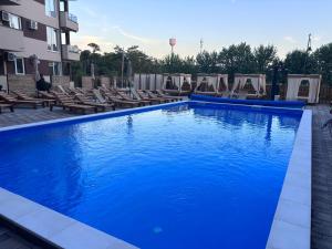 ein großer blauer Swimmingpool mit Liegestühlen neben einem Gebäude in der Unterkunft Šojmesković in Veliko Gradište