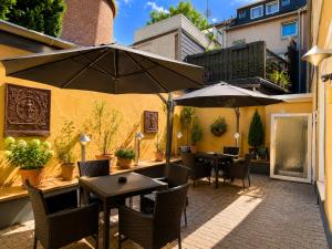 eine Außenterrasse mit Tischen, Stühlen und Sonnenschirmen in der Unterkunft WOS Hotel in Mönchengladbach