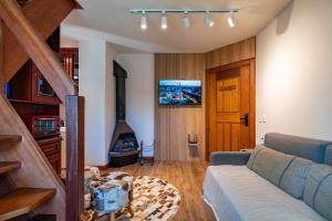 a living room with a couch and a tv at Rosa Condomínio Vale azul in Gramado