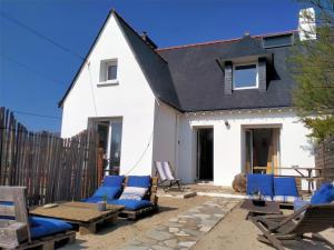 a patio with blue chairs and a white house at Surf Hostel Quiberon in Saint-Pierre-Quiberon