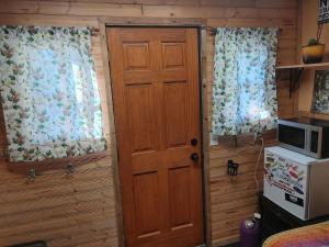 a door and two windows in a room with a microwave at Cozy Tree House in Saint John