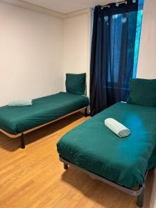 a room with two green beds and a window at Maison SYD saint-Junien in Saint-Junien