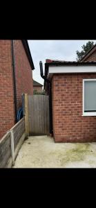 a brick building with a door and a fence at Cosy Corner Cheadle in Cheadle