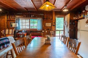 a dining room with a long table and a refrigerator at Cozy Cabin w Pavilion Deck Fireplace & FirePit in Terra Alta